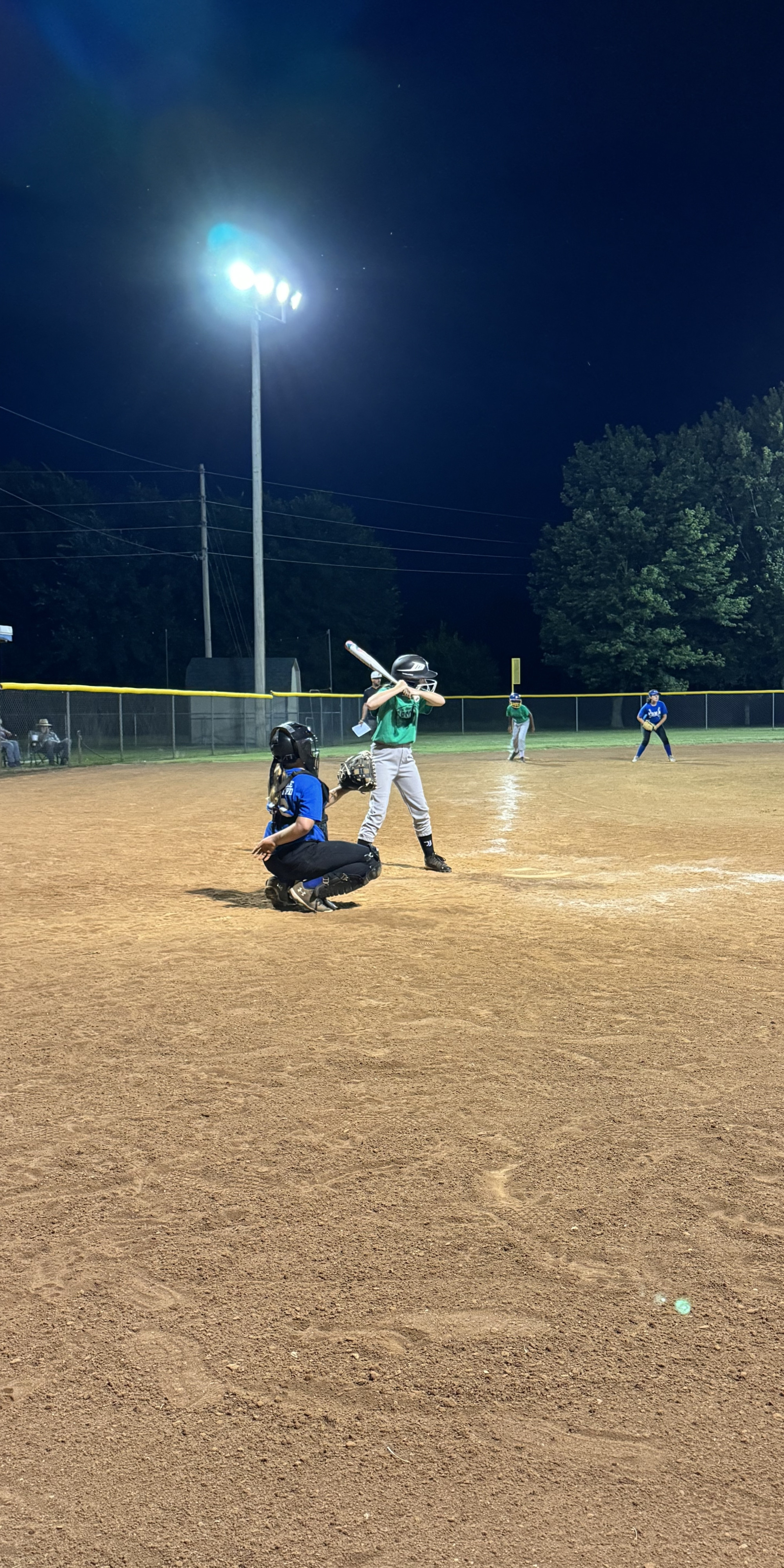 young baseball player at bat at a night game
